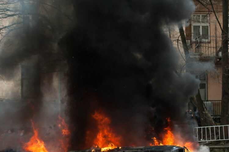 car destroyed and set on fire during the riots. city center. clouds of smoke