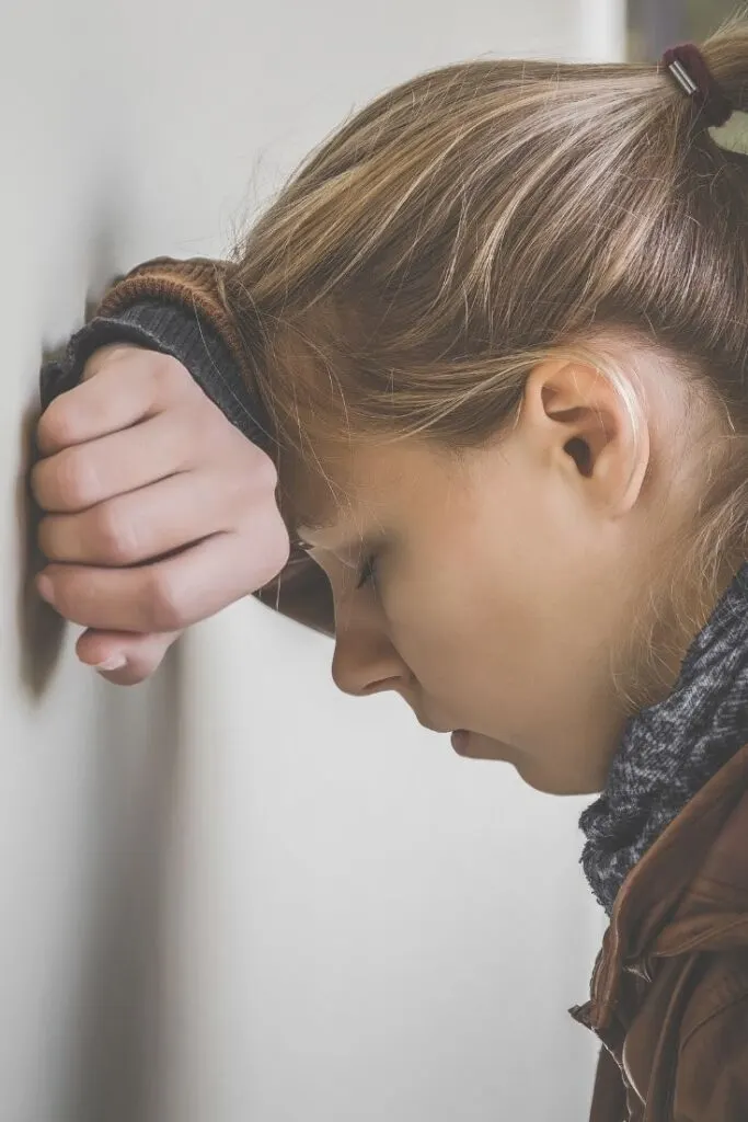 Girl leaning with head against the wall.