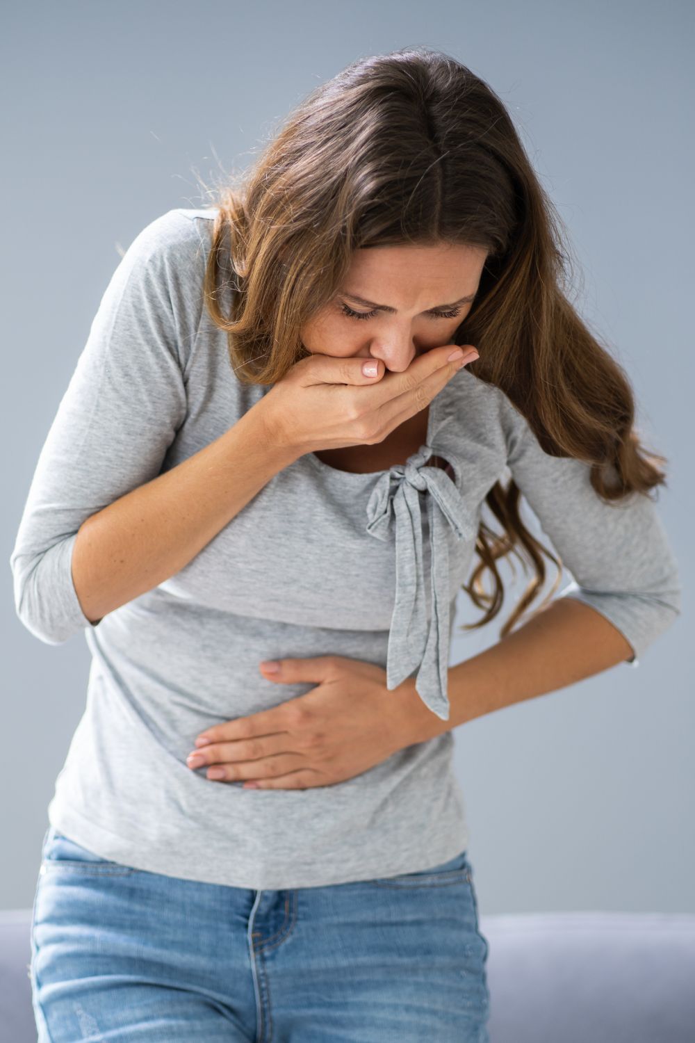 A woman holding her stomach and mouth like she might vomit. 
