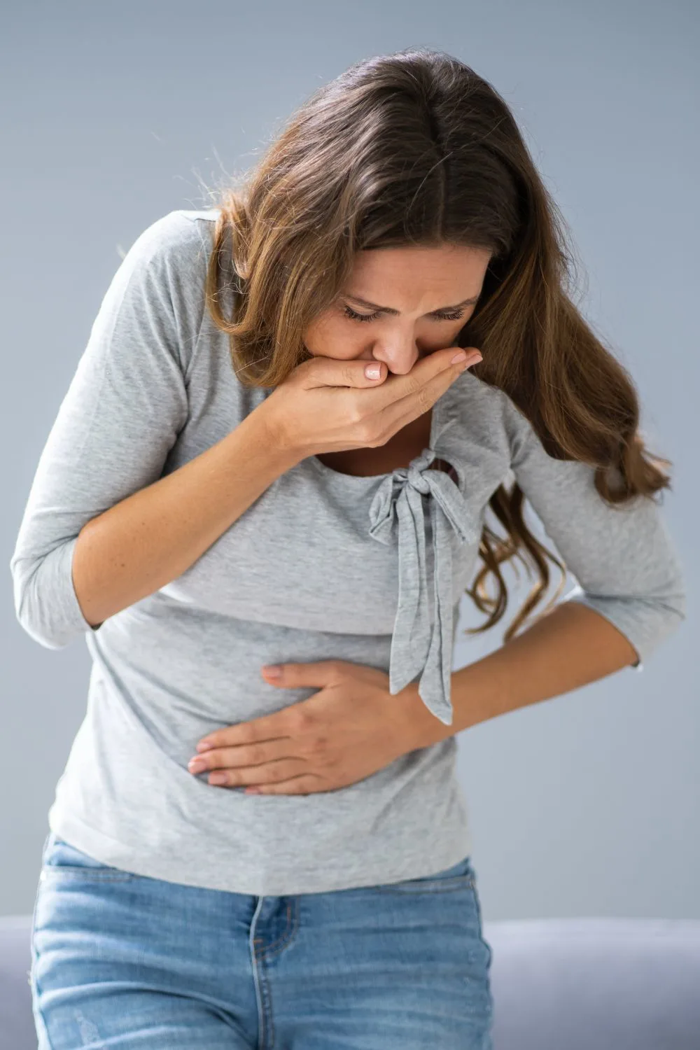 A woman holding her stomach and mouth like she might vomit.